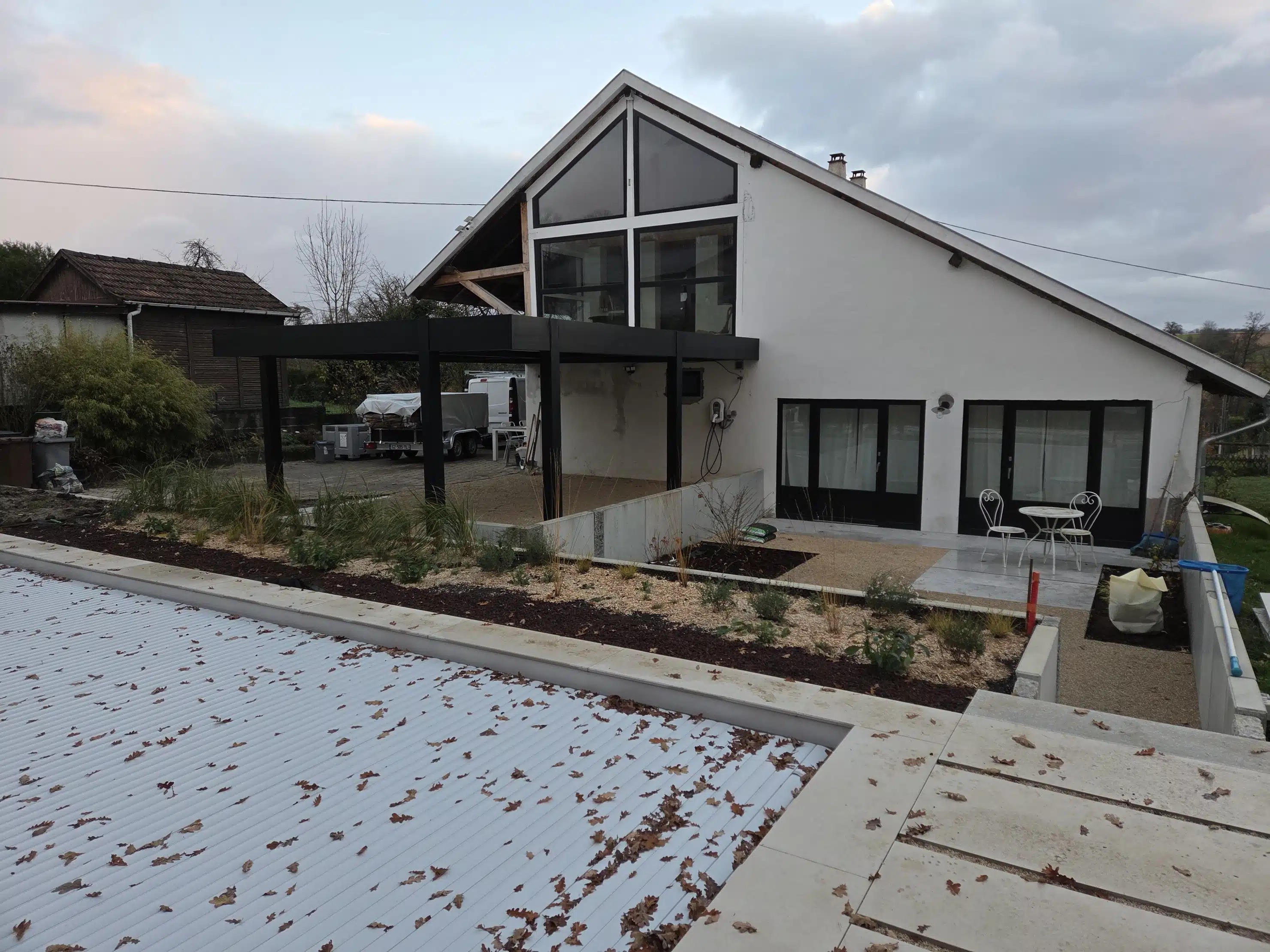 Carport double aluminium adossé vu depuis le fond du jardin à Muespach