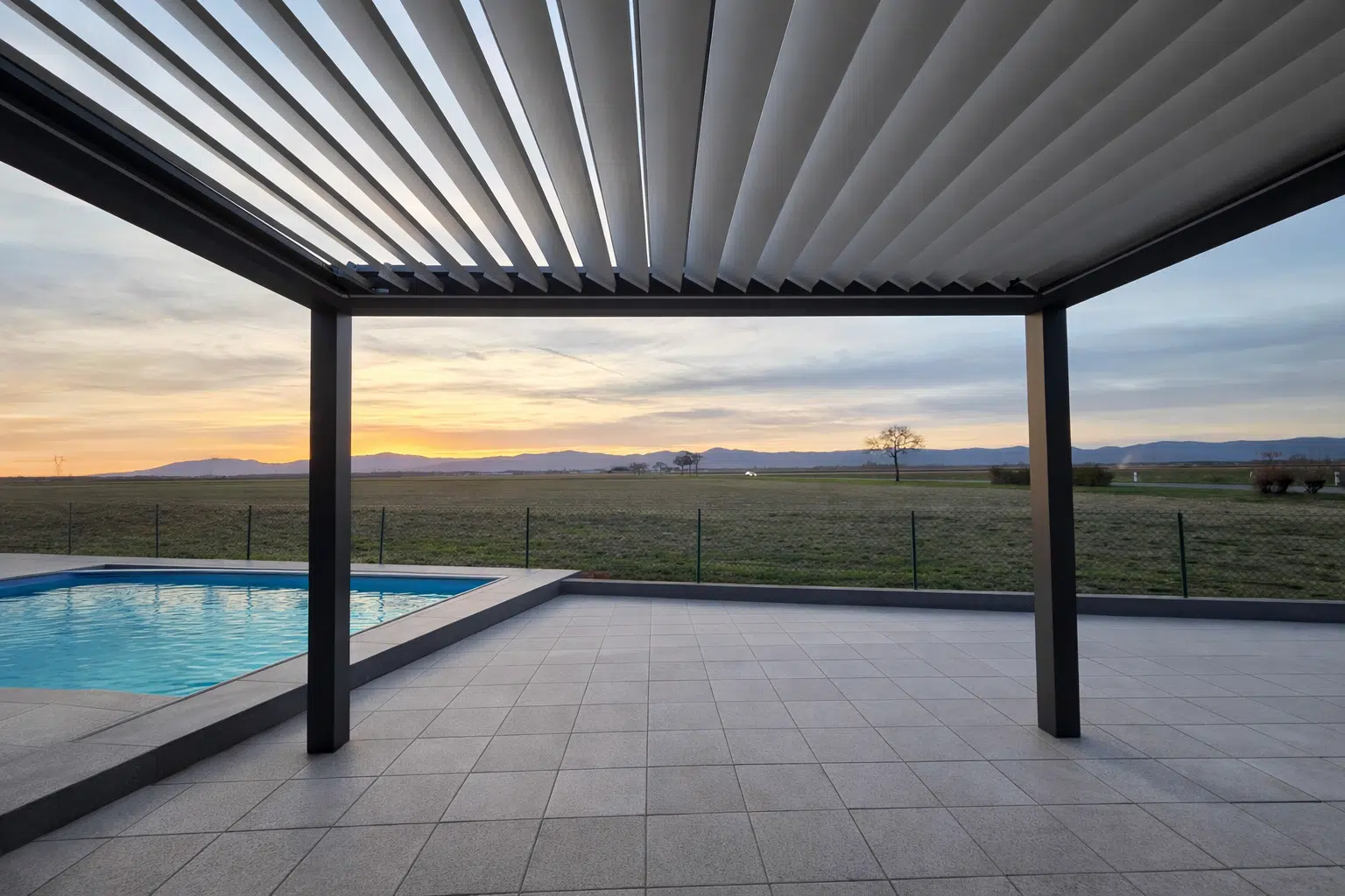 Vue depuis le dessous d’une pergola bioclimatique motorisée sur mesure avec lames orientables au coucher de soleil à Appenwihr