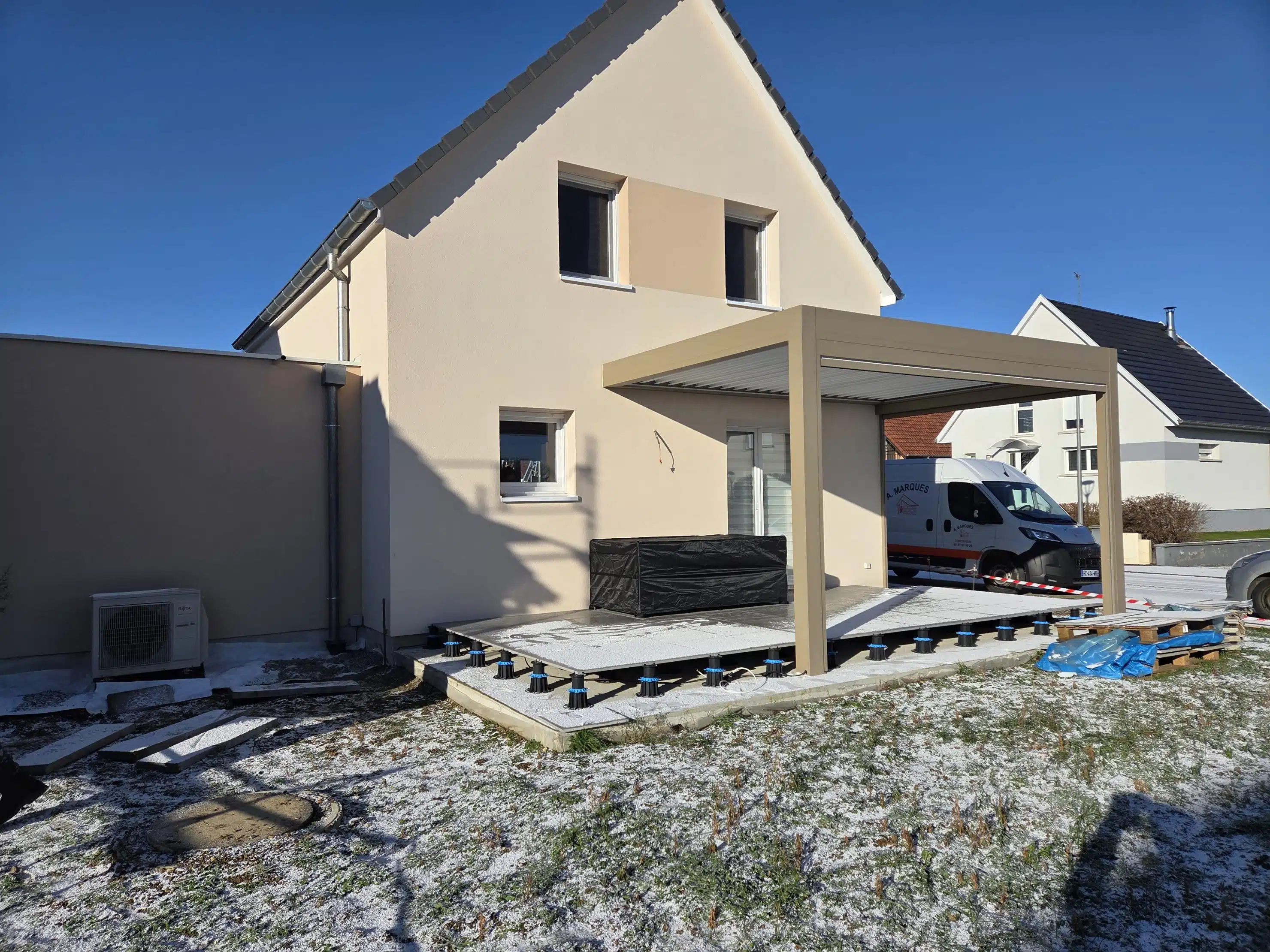 Pergola bioclimatique motorisée en aluminium couleur taupe installée sur terrasse, vue depuis le jardin à Meyenheim