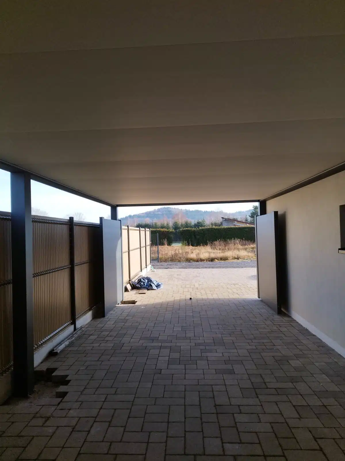 Vue intérieure vers la rue : dessous de carport aluminium et portail motorisé à Saulcy-sur-Meurthe.