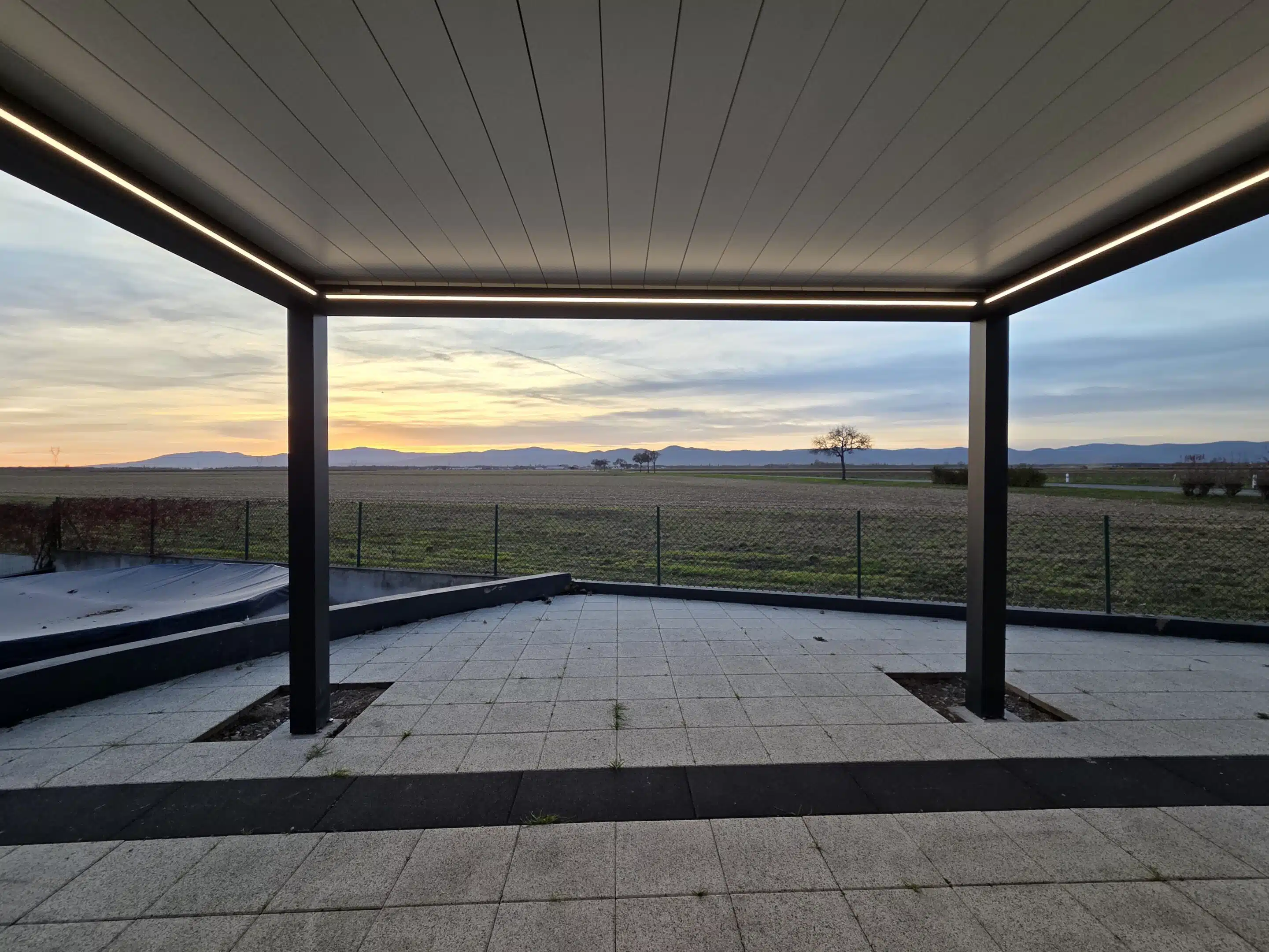 Vue sous pergola bioclimatique motorisée avec éclairage LED allumé, installation sur mesure à Appenwihr