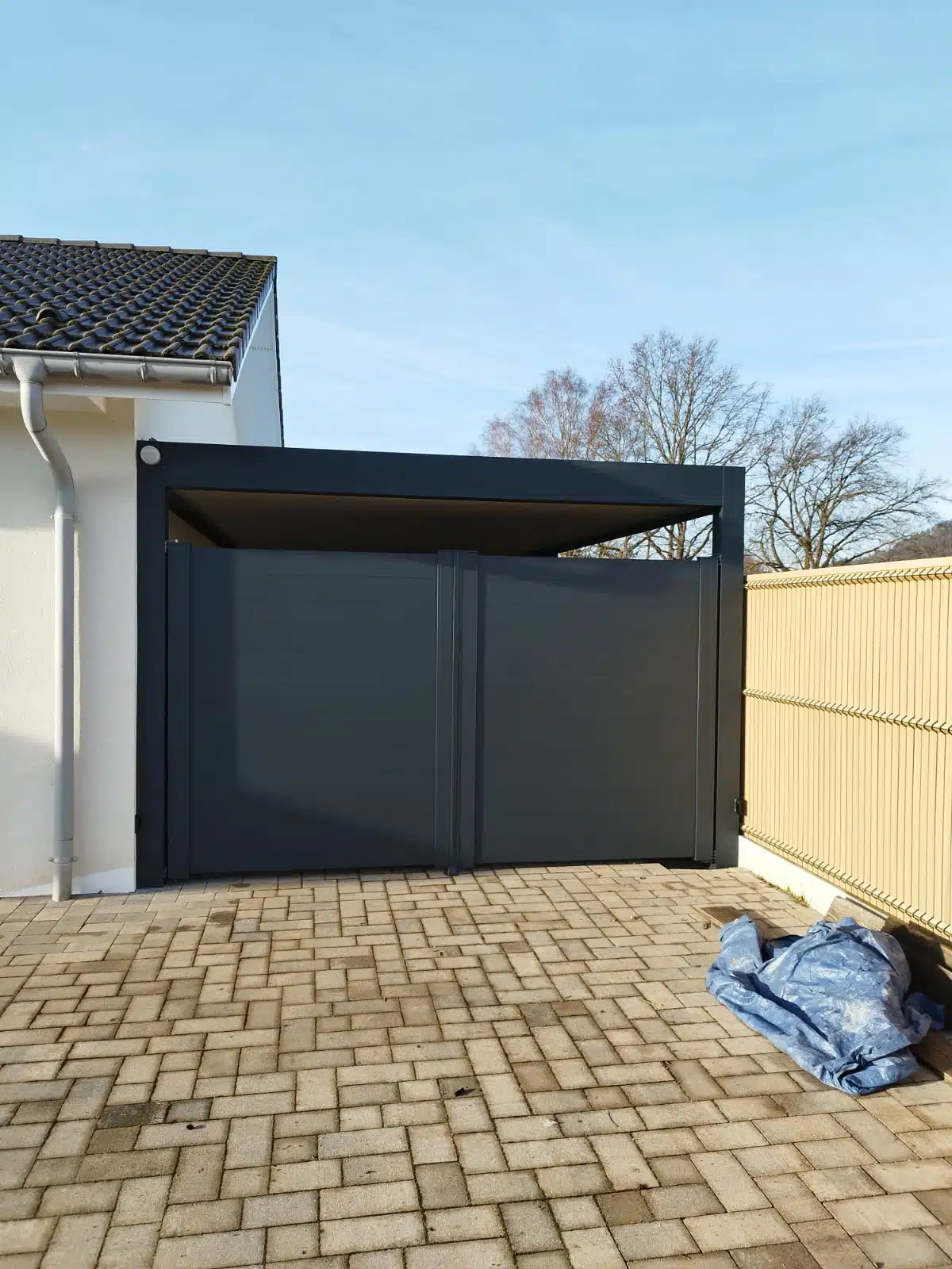 Carport aluminium avec portail fermé en façade, installation sur mesure à Saulcy-sur-Meurthe.