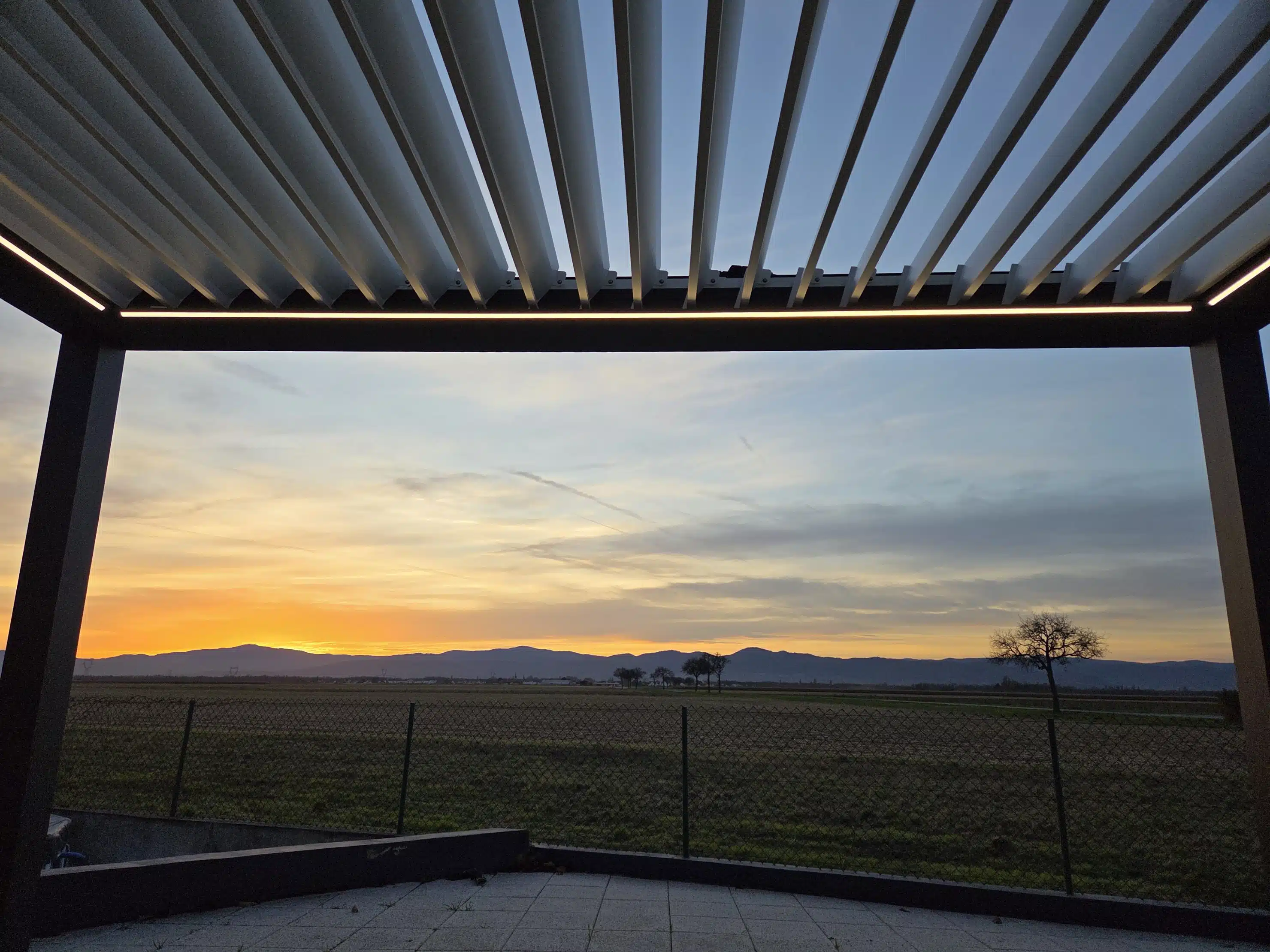 Vue intérieure du mécanisme de pergola bioclimatique motorisée au coucher du soleil, installation à Appenwihr